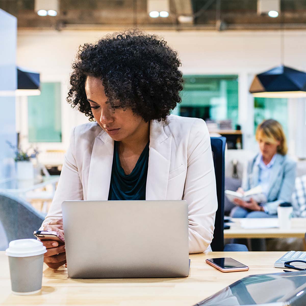 Woman sitting at desk and looking down at mobile phone