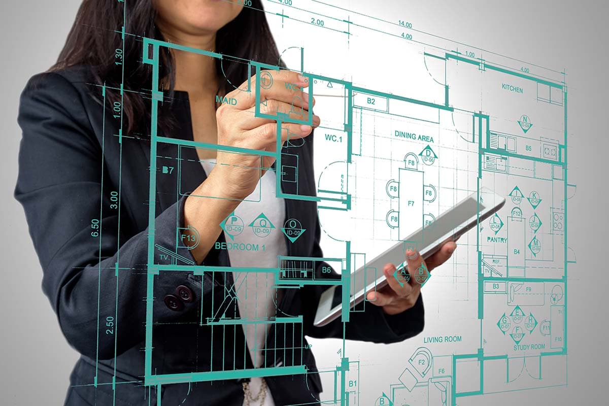 Woman drawing out blueprint for a complete home assessment on clear glass screen