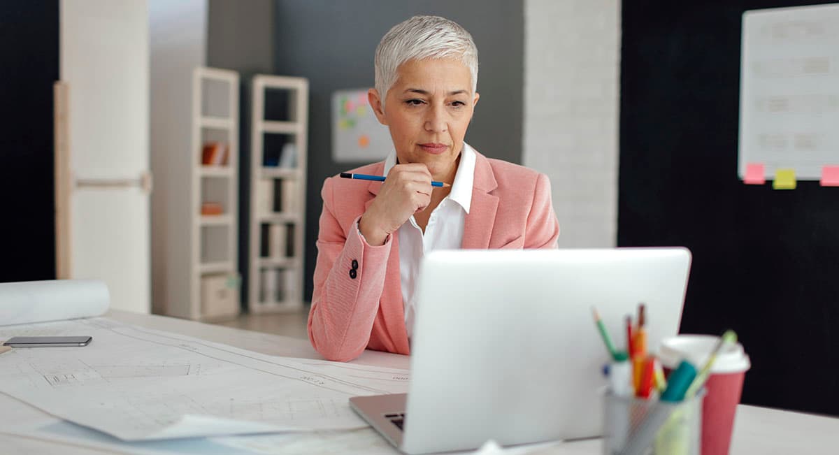 Woman sitting at a desk with blueprints and laptop