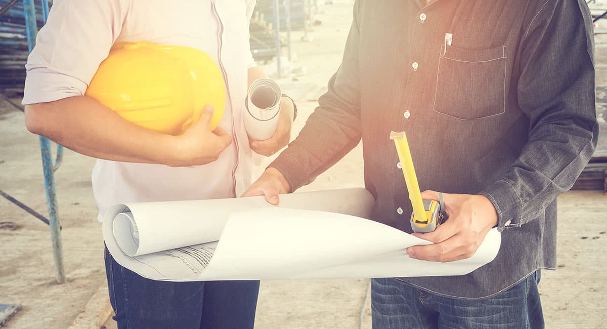 Two construction works reviewing blueprints on a jobsite