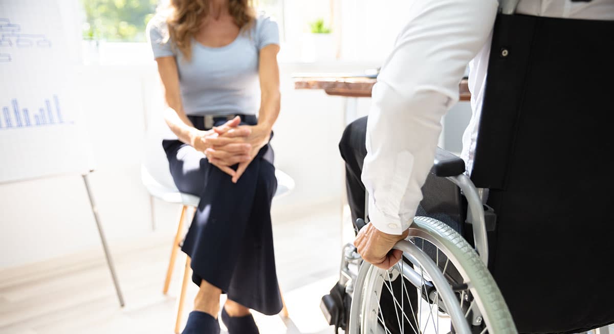 Woman sitting across from an injured worker in a wheelchair